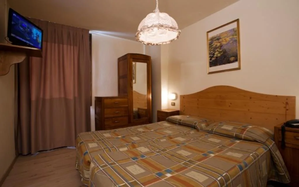 Camera matrimoniale con TV, armadio in legno e lampadario