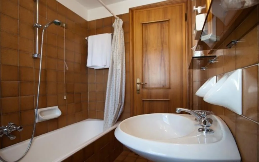 Bagno con vasca, doccia, lavabo e piastrelle marroni