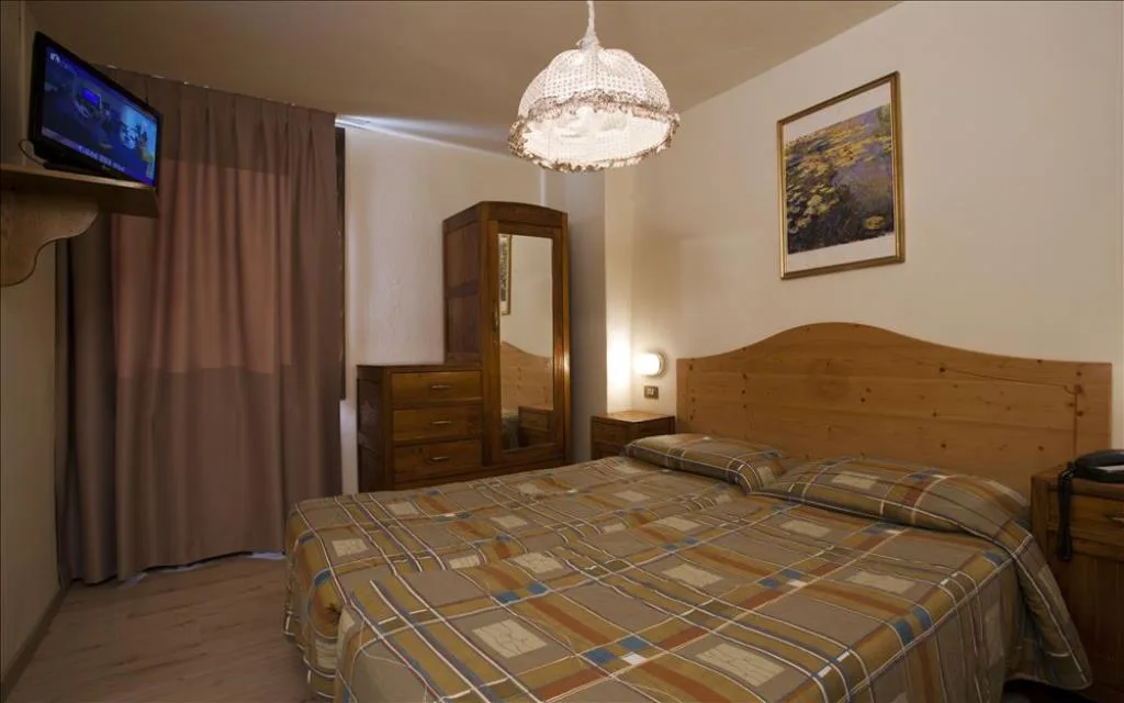 Camera matrimoniale con arredi in legno, TV e lampadario a soffitto