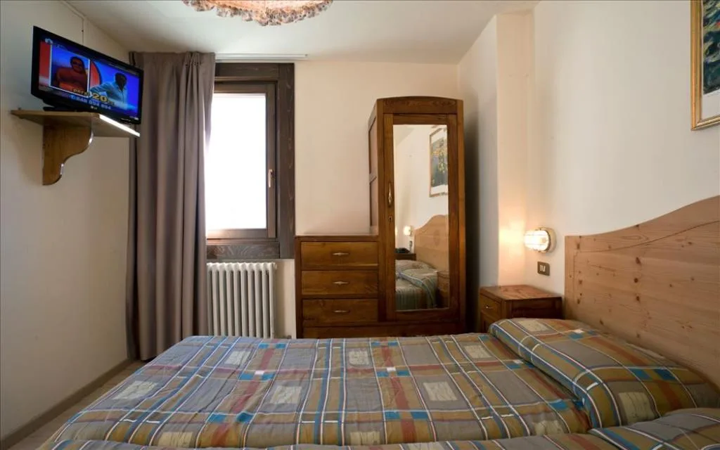 Camera con letto matrimoniale, TV a parete e cassettiera in legno