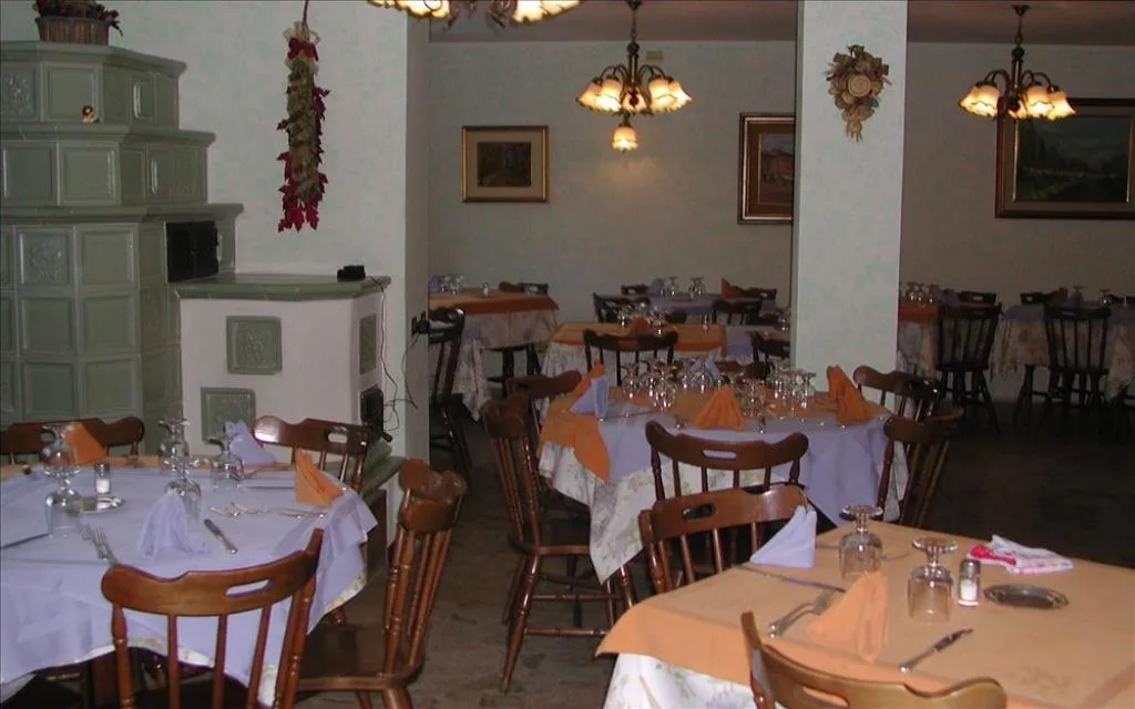 Sala ristorante con tavoli apparecchiati e stufa in maiolica
