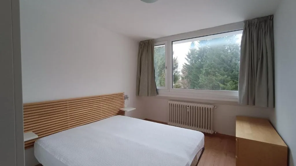 Camera da letto matrimoniale con testiera in legno e finestra affacciata sul verde