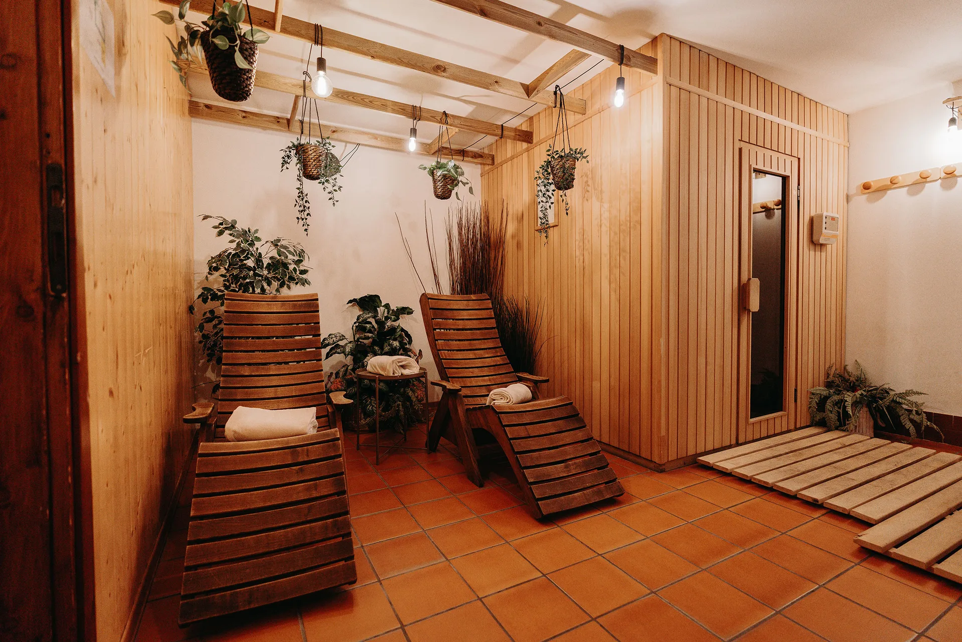 Zona relax della spa con lettini in legno, piante e sauna