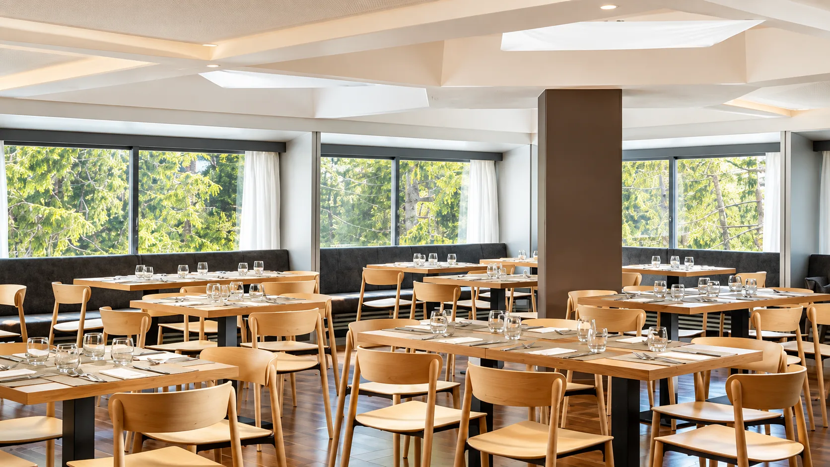 Sala ristorante luminosa con tavoli in legno e vetrate affacciate sul bosco