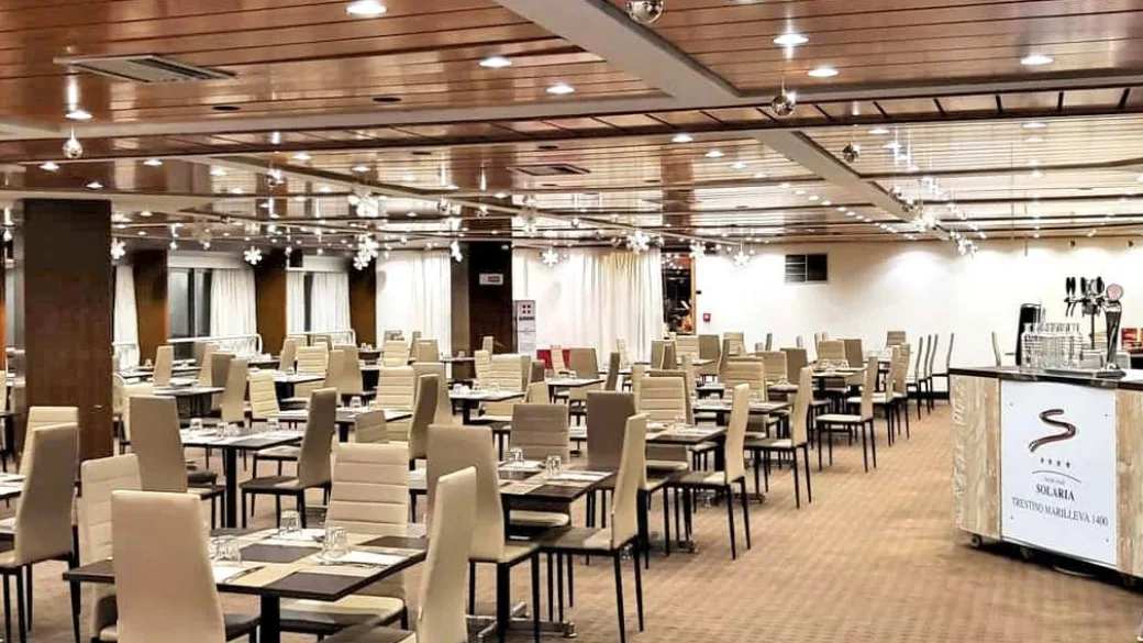 Sala ristorante ampia e luminosa con tavoli apparecchiati e sedie beige