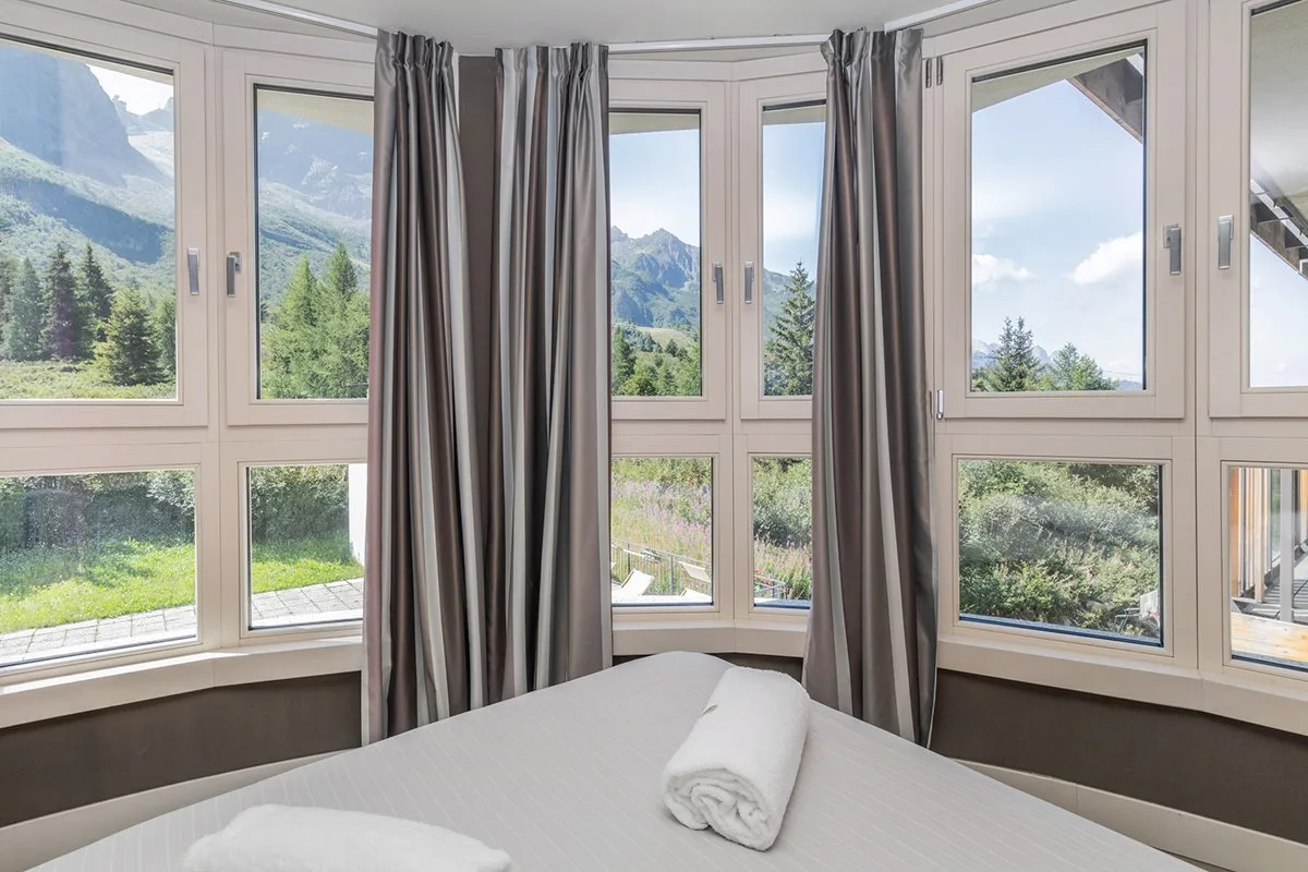 Camera con ampie finestre panoramiche affacciate su montagne e bosco