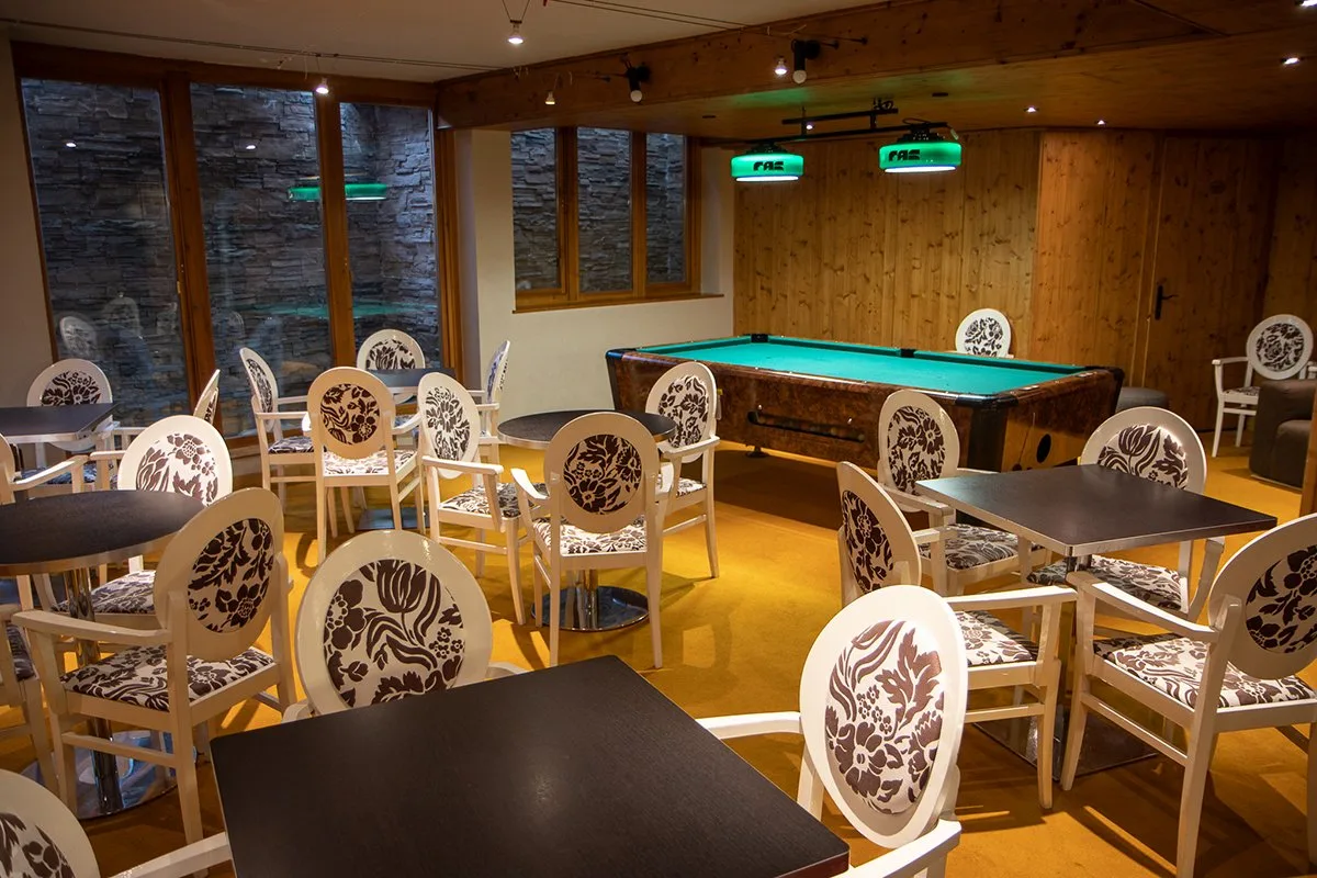 Sala con tavolo da biliardo, tavoli e sedie decorate con vetrate in pietra