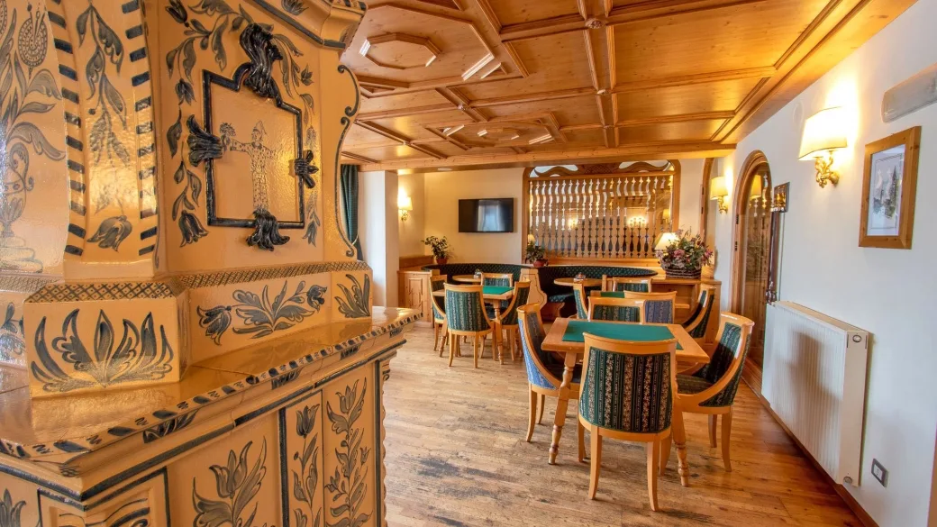 Sala da gioco con stufa in maiolica decorata, tavoli da carte e soffitto in legno