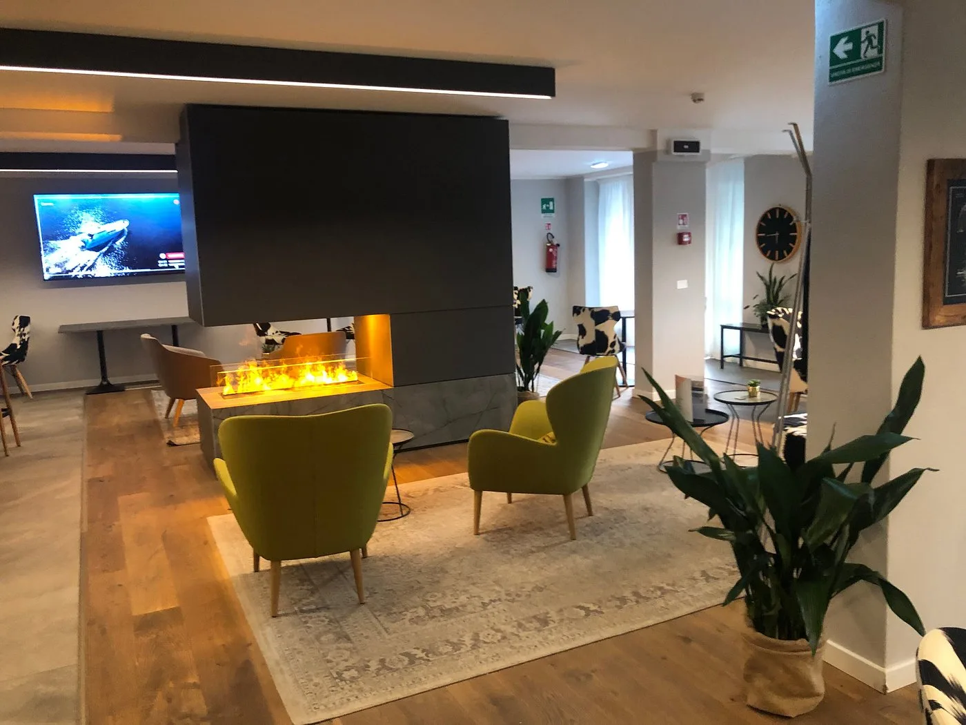 Area lounge con camino moderno, poltrone gialle e TV a parete