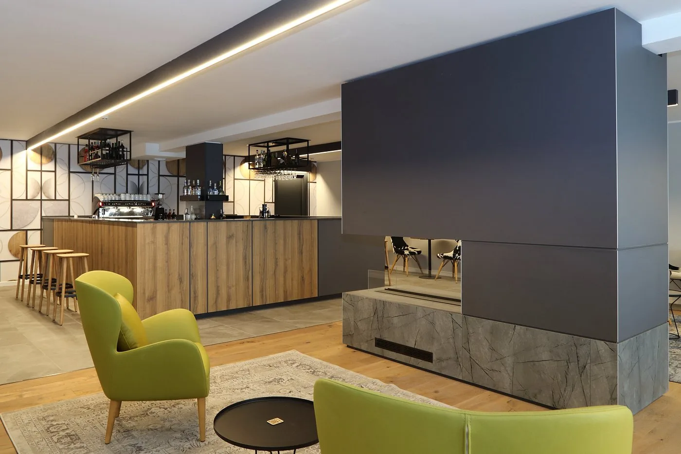 Lounge con bar, camino centrale e poltrone verdi