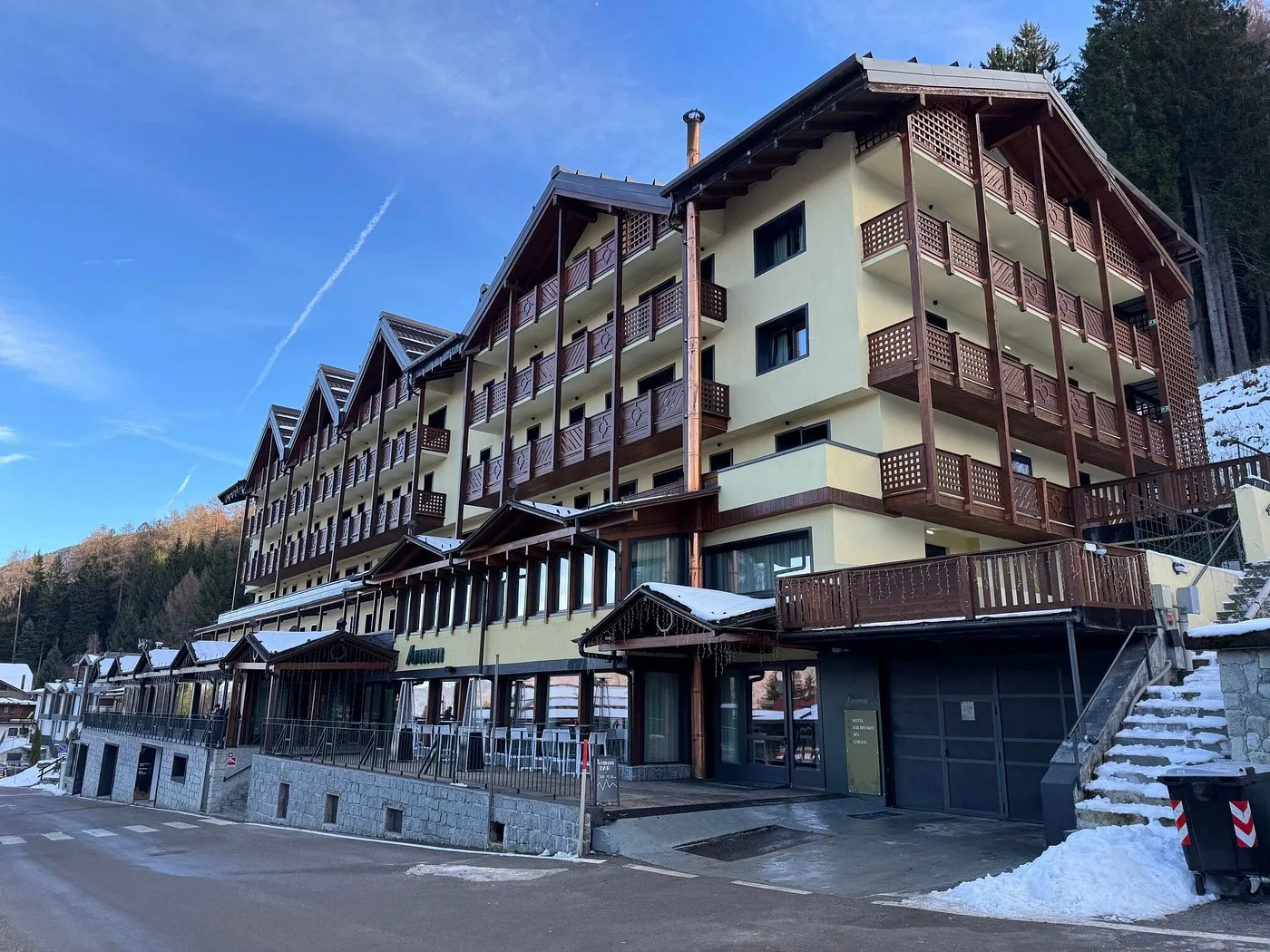 Vista esterna dell'hotel in stile chalet con balconi in legno e cielo azzurro