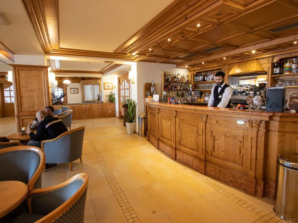 Bar dell'hotel con bancone in legno intagliato e barista in servizio
