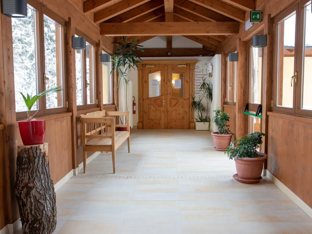 Corridoio interno con travi in legno, panca e piante che conduce alla zona spa