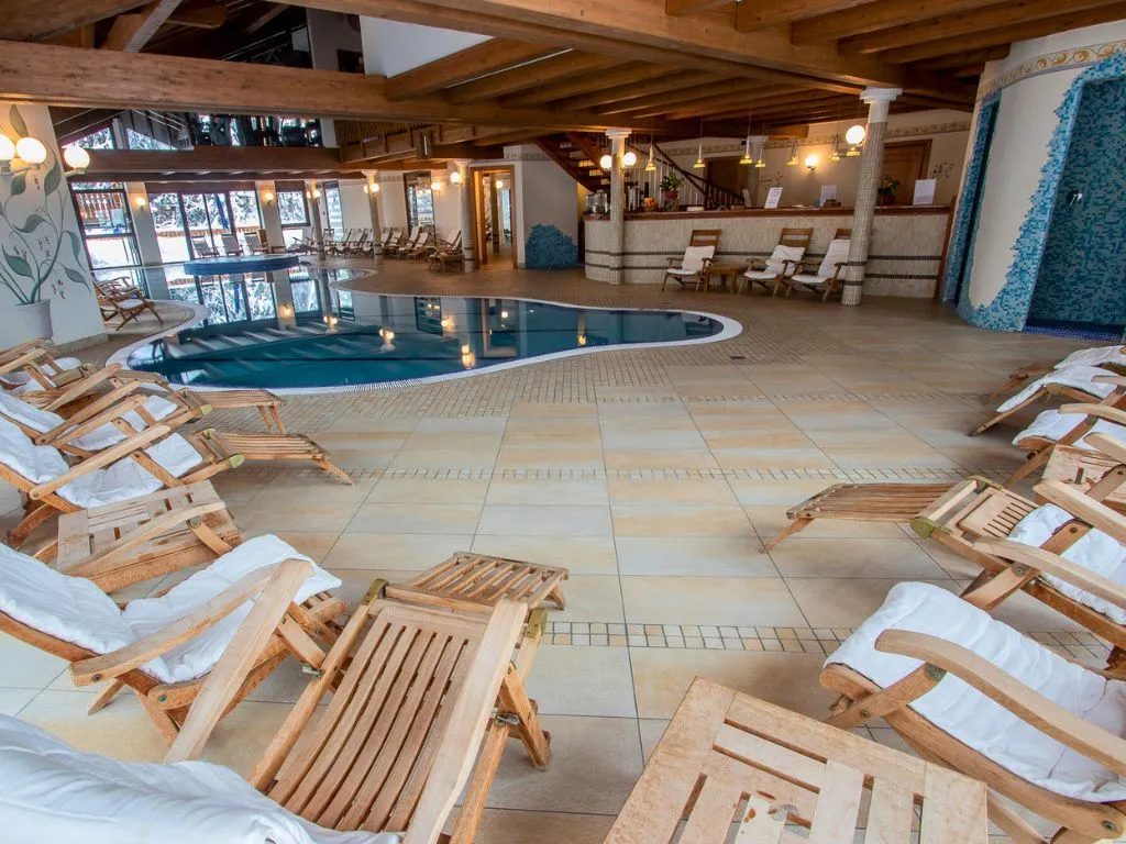 Area relax della piscina coperta con lettini in legno e zona bar