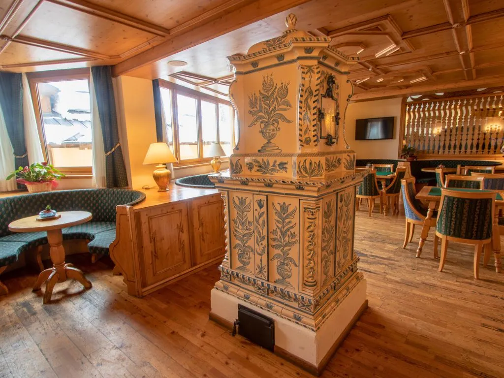 Sala soggiorno con stufa in maiolica decorata e angolo carte da gioco