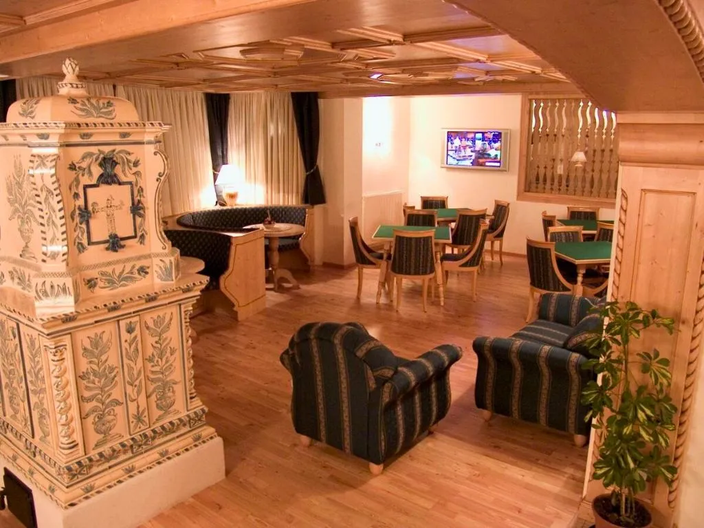 Sala comune con stufa in ceramica dipinta, poltrone e tavoli da gioco