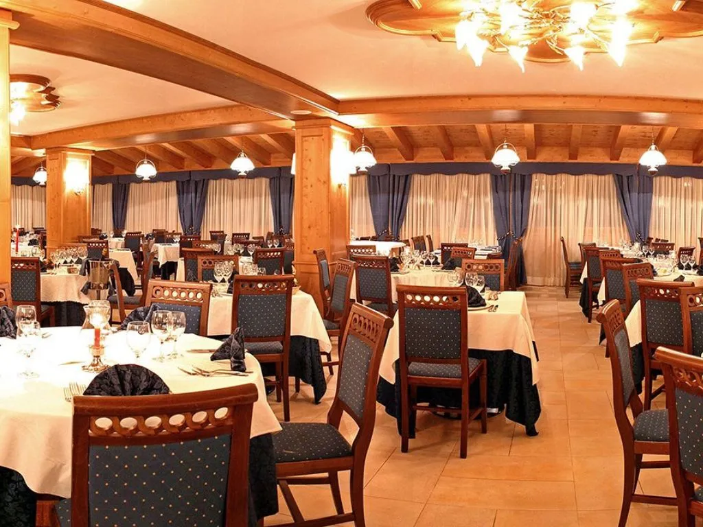 Sala ristorante con tavoli apparecchiati, travi in legno e tende blu