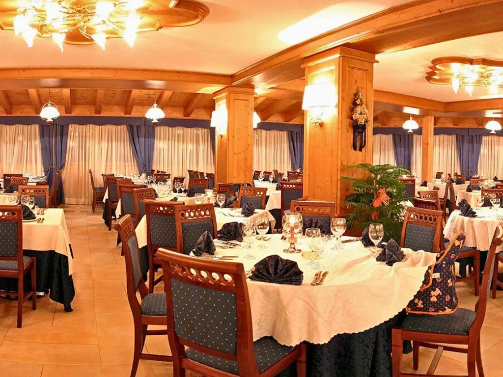 Sala ristorante elegante con tavoli rotondi apparecchiati e lampadari