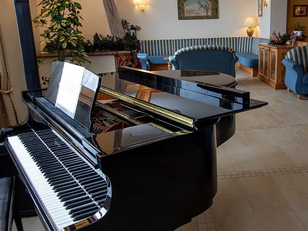Pianoforte a coda nero nella hall con divani azzurri sullo sfondo