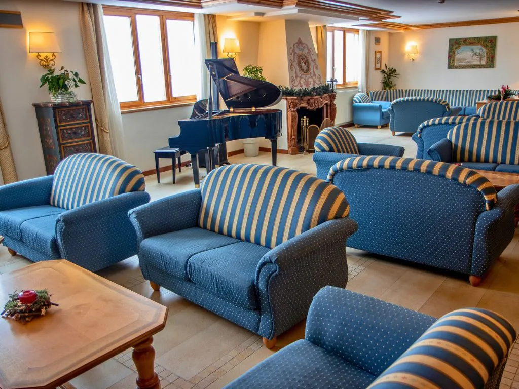 Salotto con divani a righe blu, pianoforte a coda e camino in pietra