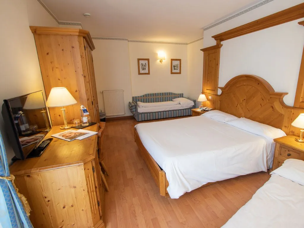 Camera con letto matrimoniale, divano e arredi in legno di pino