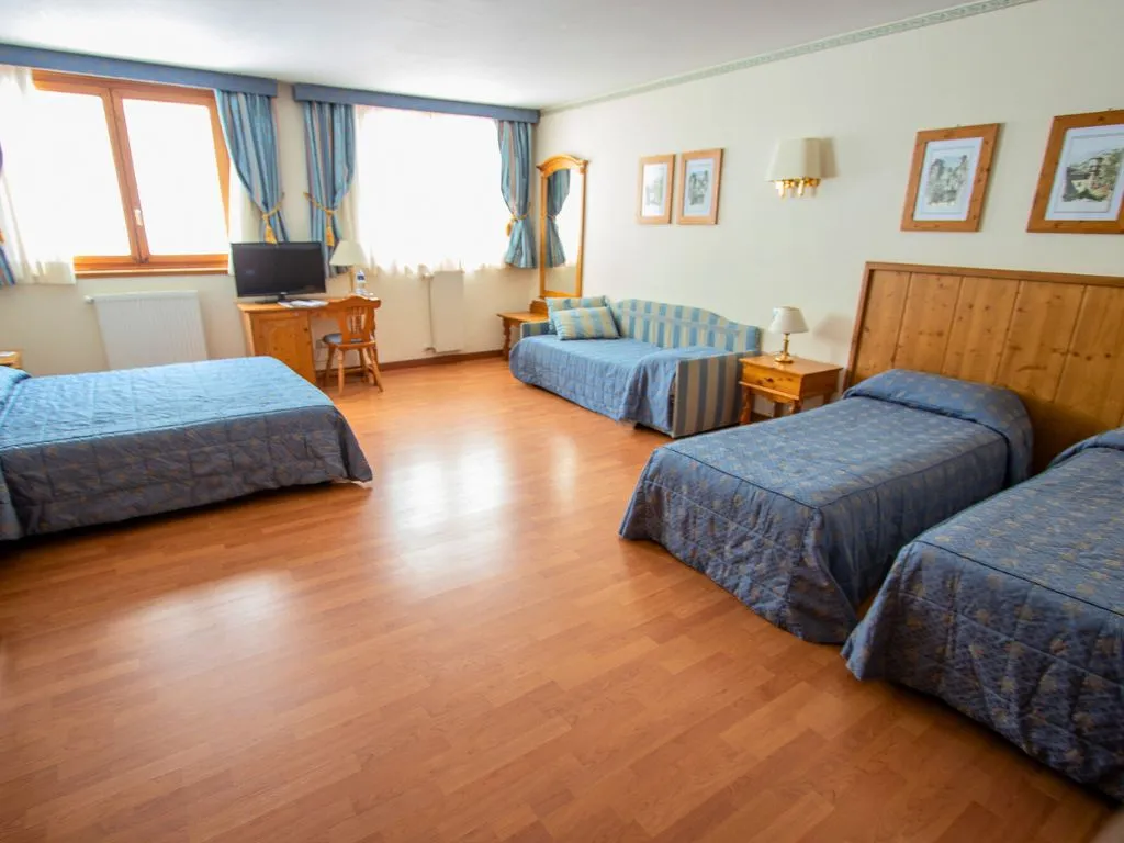 Camera familiare ampia con più letti, divano e parquet