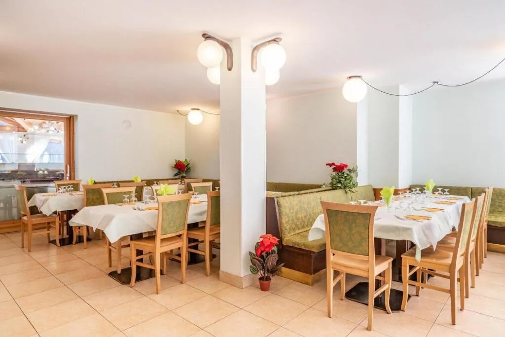 Sala ristorante con tavoli apparecchiati, sedute verdi e pavimento chiaro