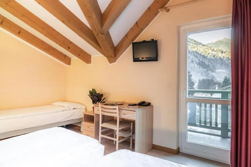 Camera mansardata con letti, scrivania e balcone con vista sulle montagne