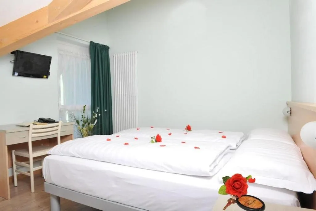 Camera matrimoniale con letto decorato con petali di rosa e scrivania