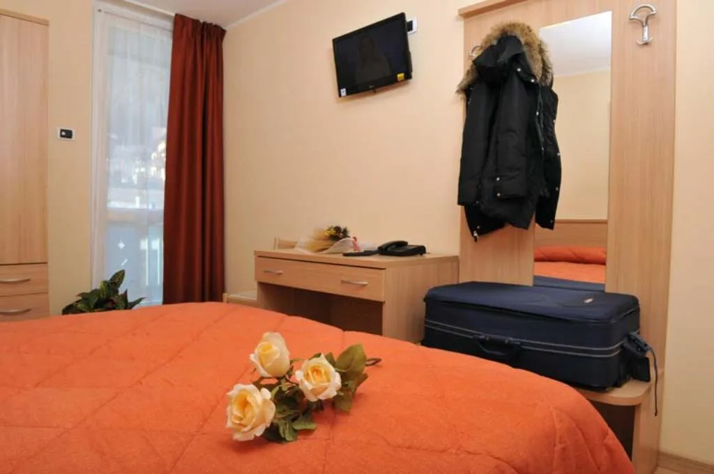 Camera con letto dal copriletto arancione, TV a parete e scrivania in legno