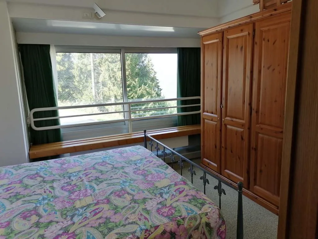 Camera da letto con armadio in legno e ampia finestra con vista sugli alberi
