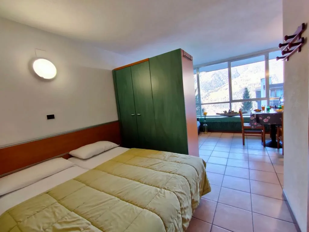 Camera con letto matrimoniale, armadio verde e vista sulle montagne