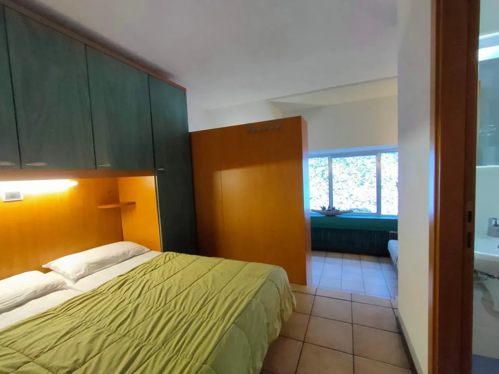 Camera da letto con armadi verdi e in legno e bagno adiacente