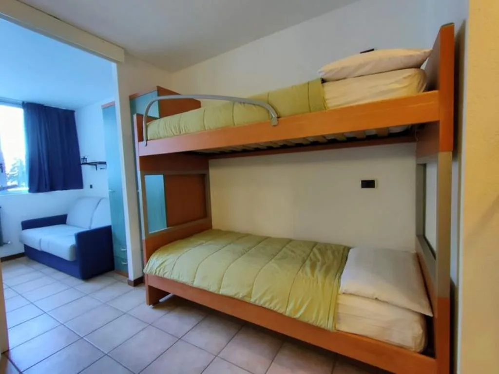 Camera con letto a castello in legno e divano bianco
