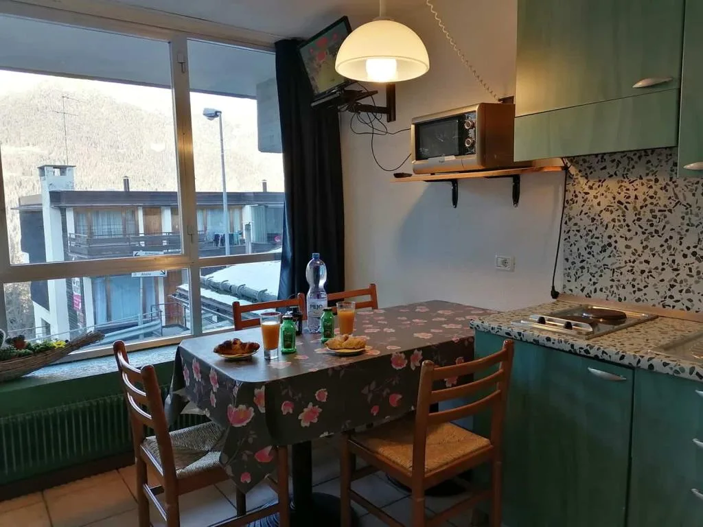 Cucina con tavolo apparecchiato e finestra con vista sugli edifici e la valle