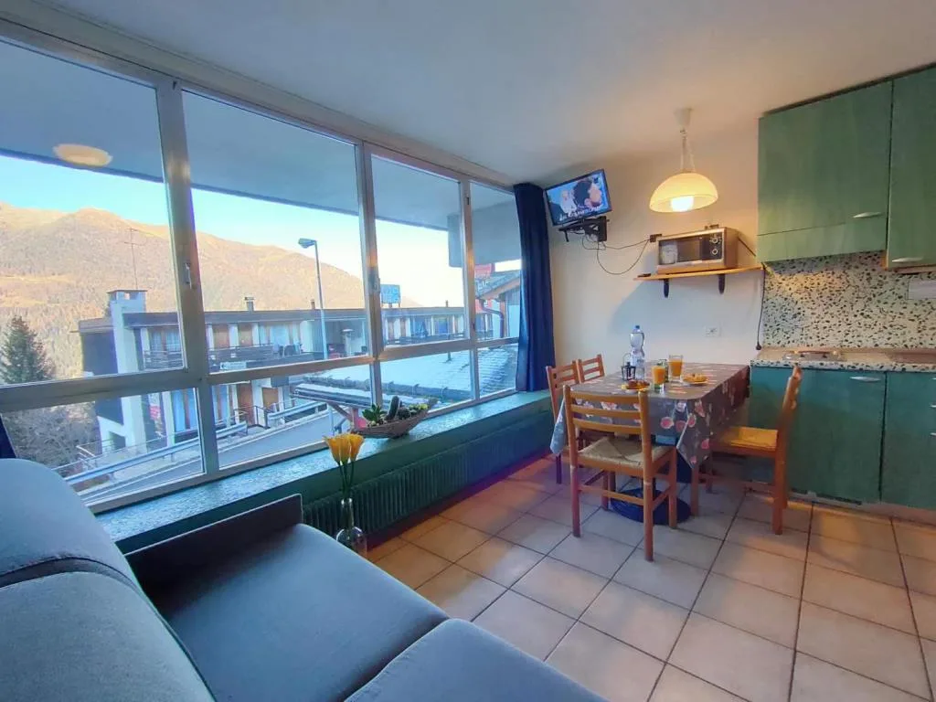 Zona giorno con cucina e grande finestra con vista sulla valle alpina