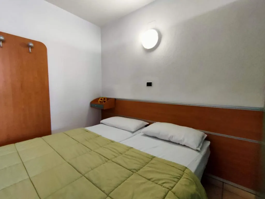 Camera con letto matrimoniale, testiera in legno e applique tonda