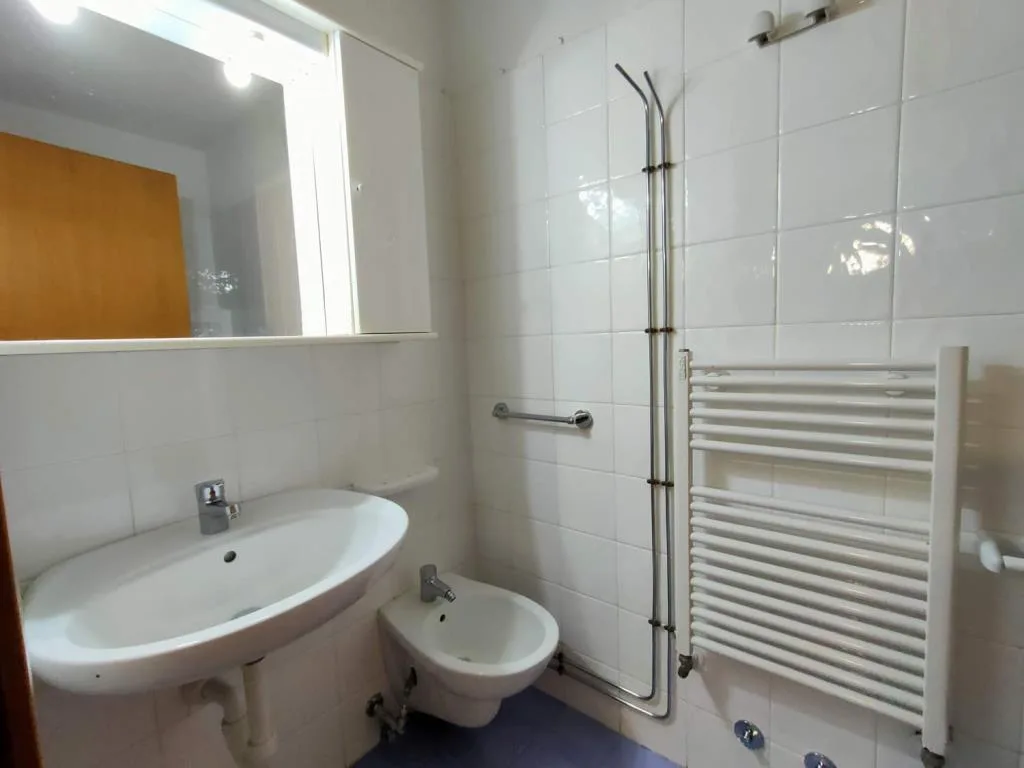 Bagno con lavabo, bidet, specchio e termoarredo bianco