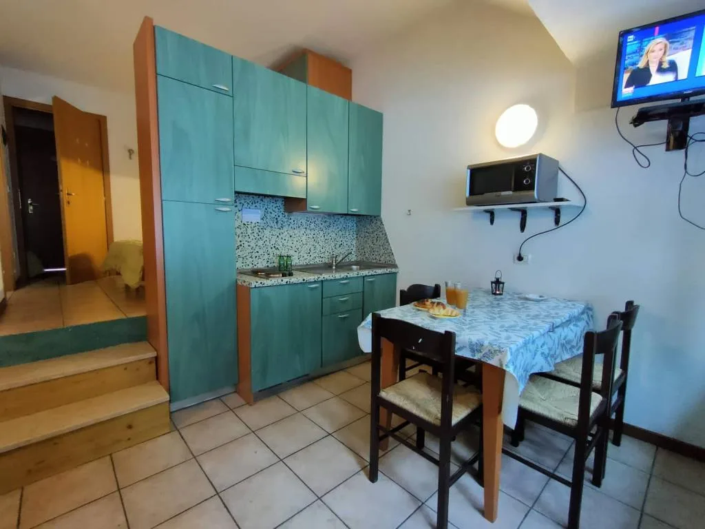 Cucina compatta verde con tavolo, TV e scaletta interna