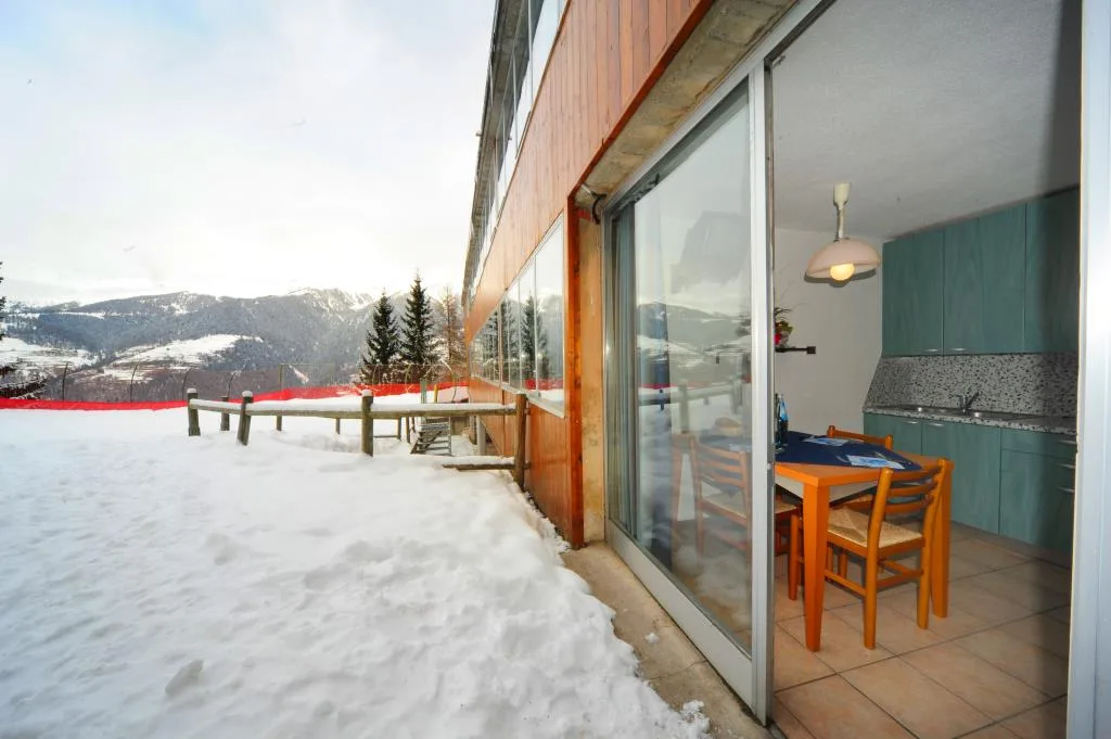 Terrazza innevata dell'appartamento con vista sulle montagne e cucina interna