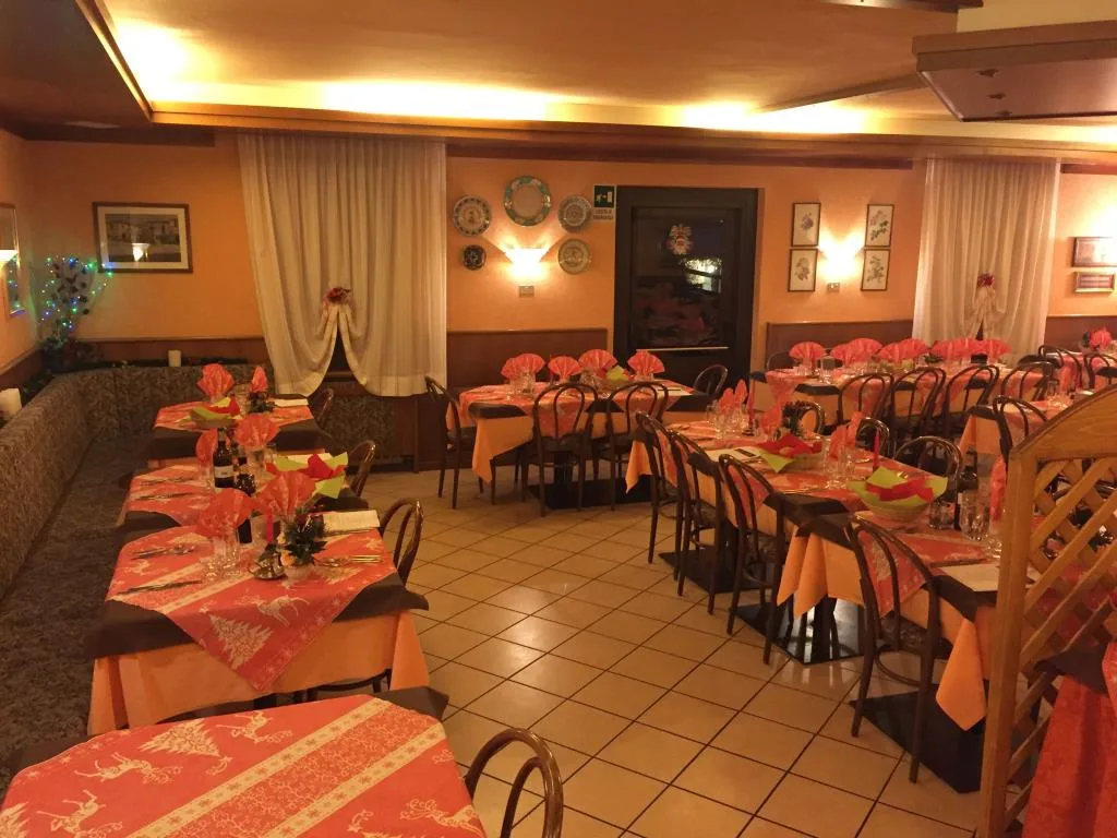 Sala da pranzo con tavoli apparecchiati, tovaglie arancioni e pavimento in piastrelle