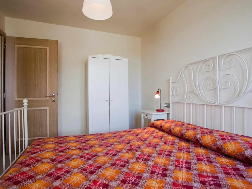 Camera da letto con letto in ferro battuto bianco, armadio e comodino