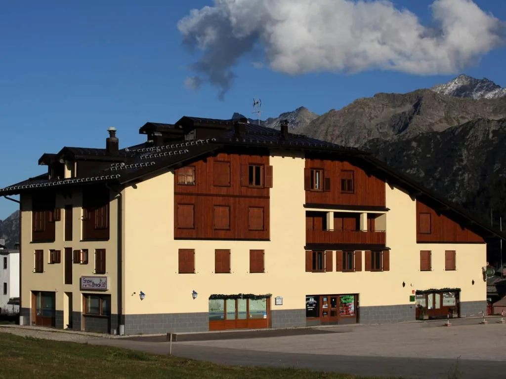 Esterno dell'edificio dell'hotel in stile alpino con montagne sullo sfondo
